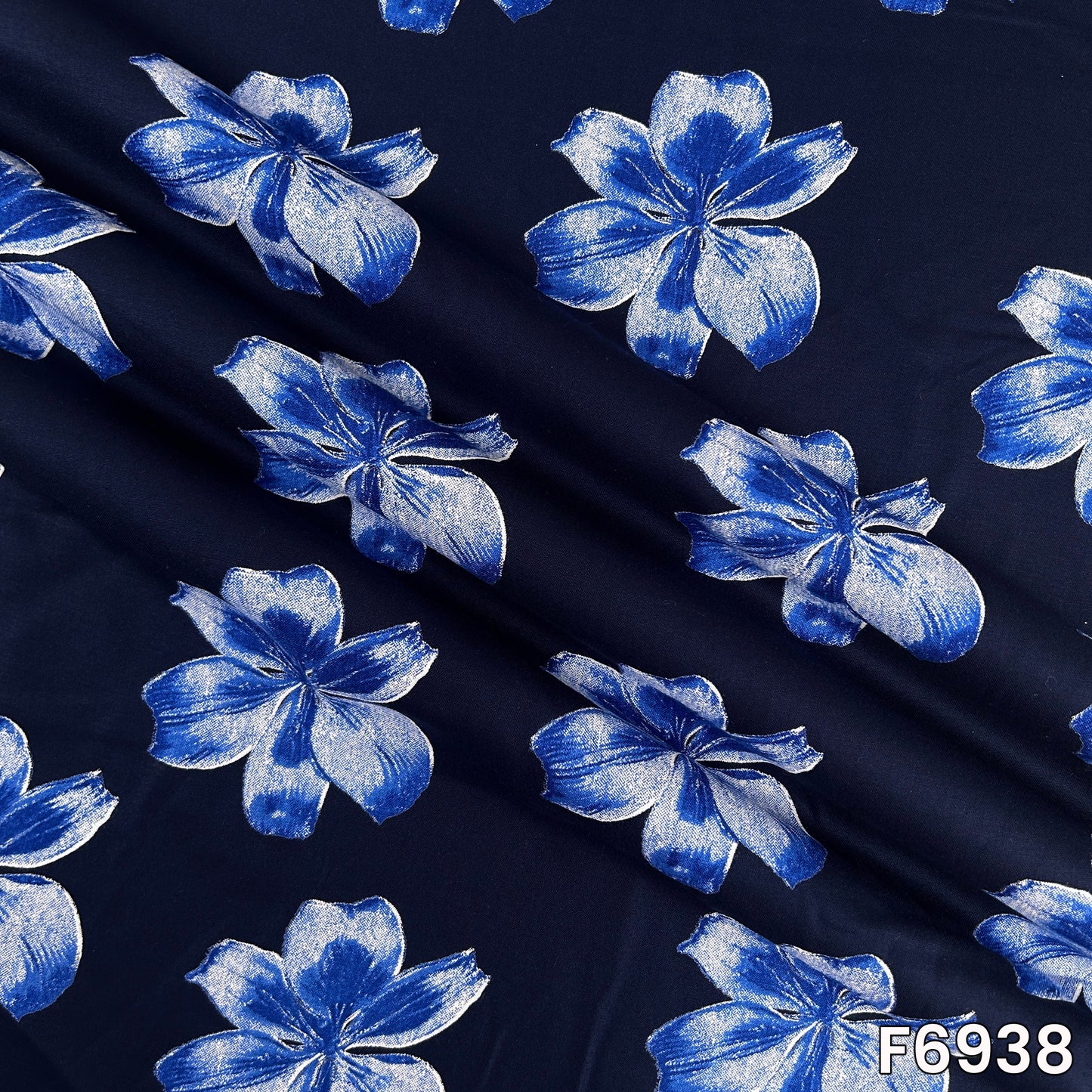 Folded F6938 rayon fabric displaying soft drape, flowing texture and bold floral print placement