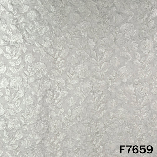 Ivory raw silk fabric with intricate white floral embroidery and textured finish