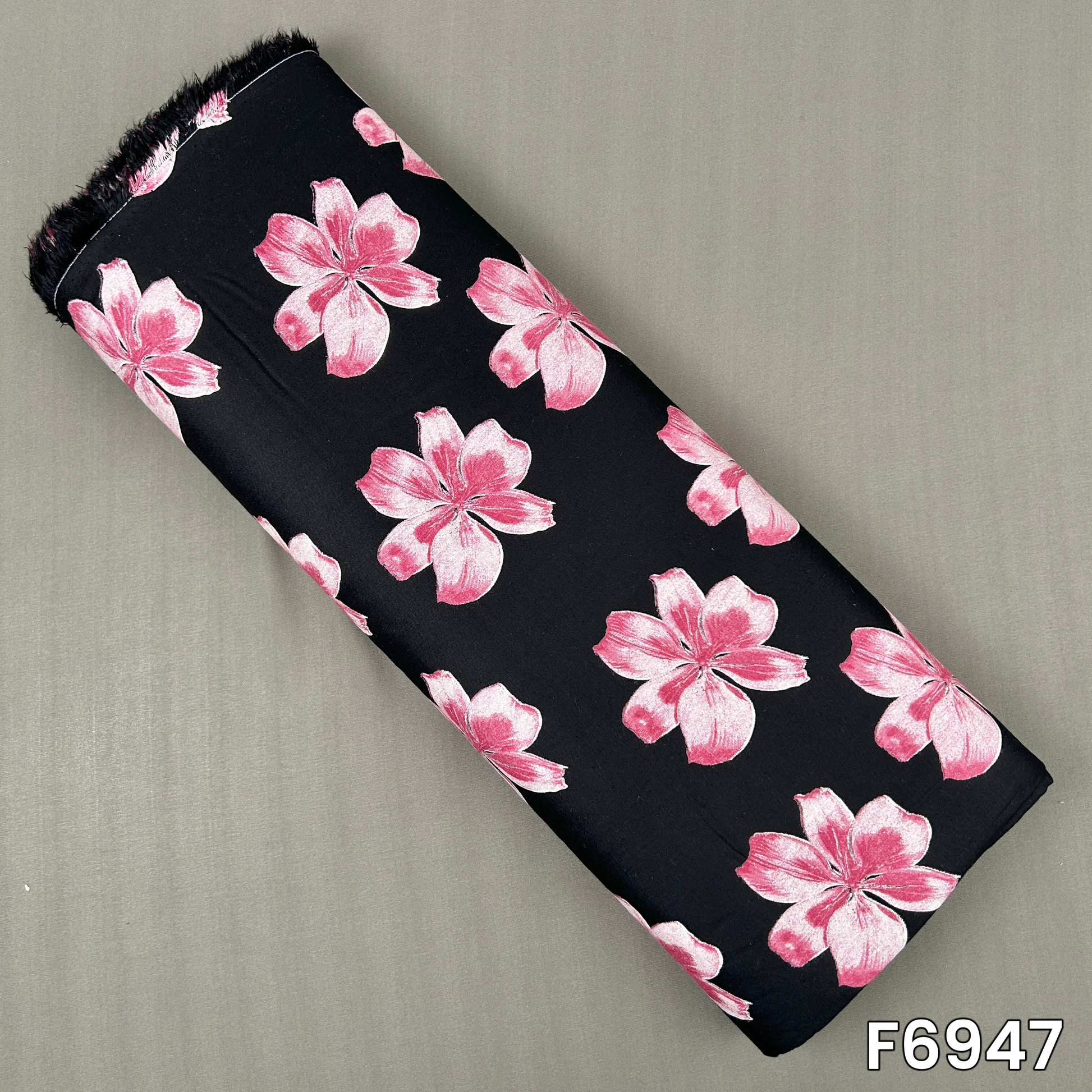 Black printed rayon fabric F6947 featuring large pink flowers scattered across a smooth dark base