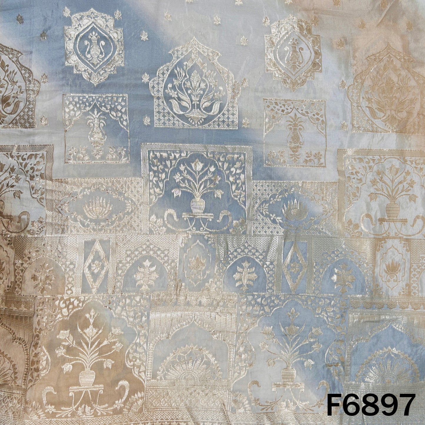 Close-up of F6897 shimmer tissue fabric showing silver zari motifs with soft blue ombre shading