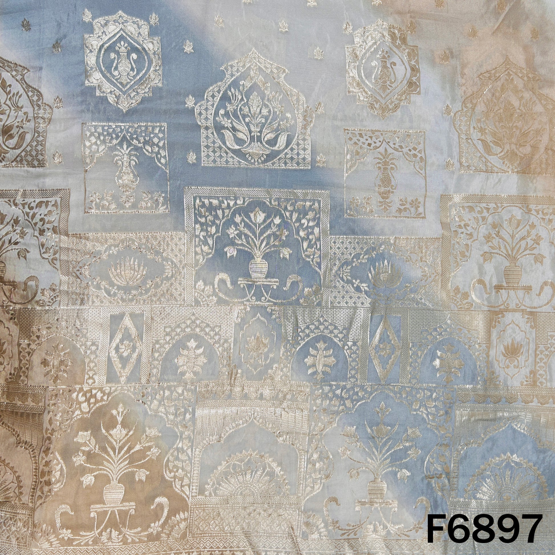 Close-up of F6897 shimmer tissue fabric showing silver zari motifs with soft blue ombre shading