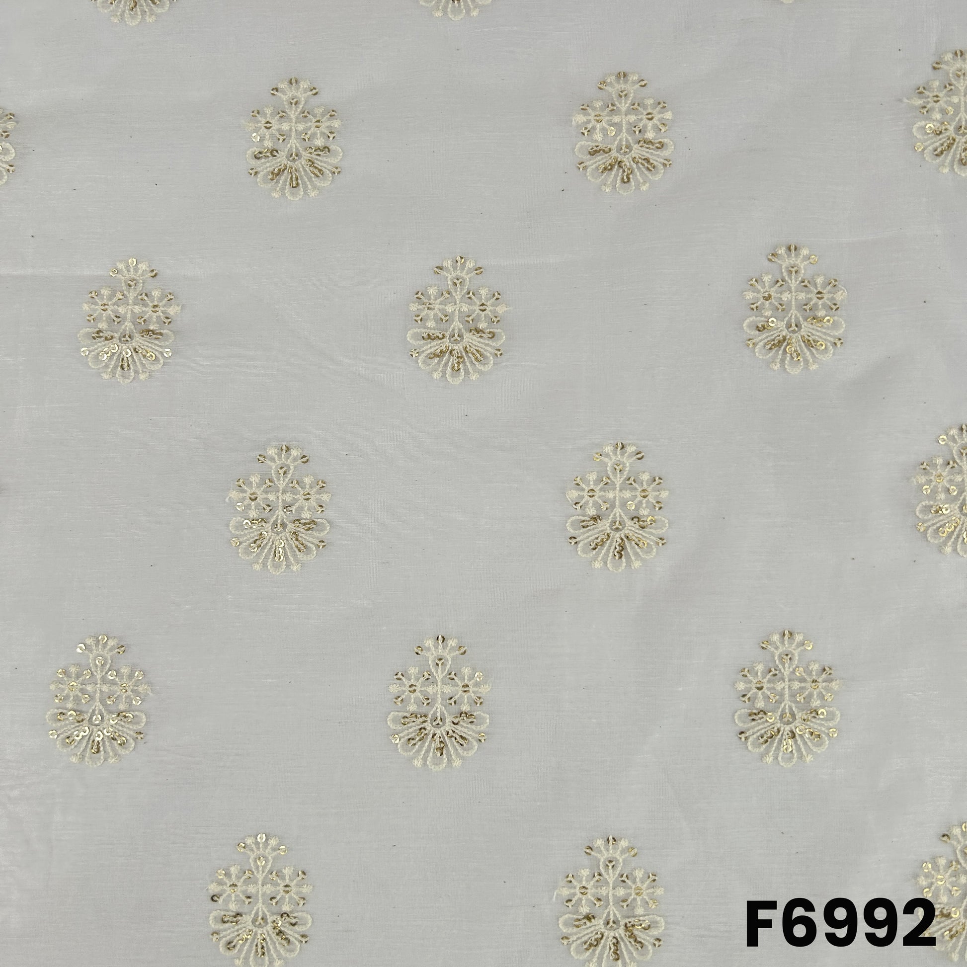 Close pattern view of F6992 highlighting golden floral butti motifs across a lightweight dyeable silk base