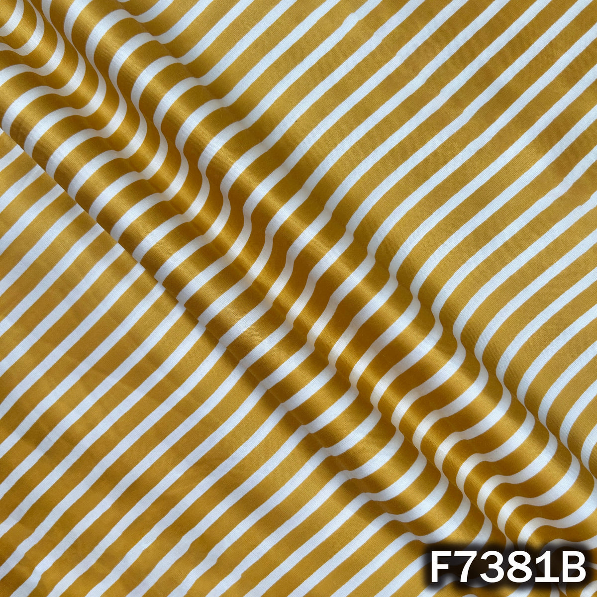 Draped mustard yellow modal satin fabric with white stripe pattern