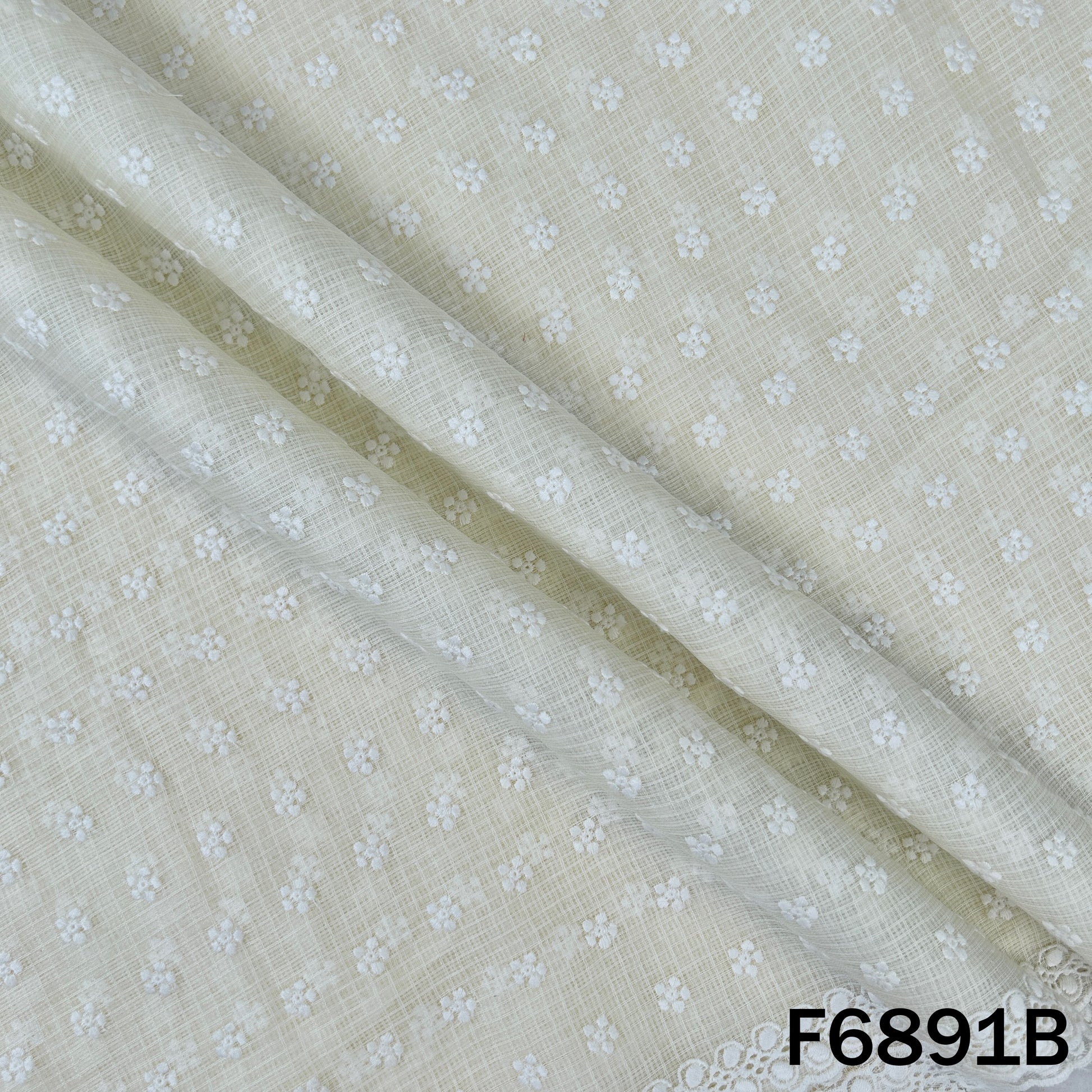 Detailed view of F6891B ivory cotton fabric highlighting its neat floral thread work